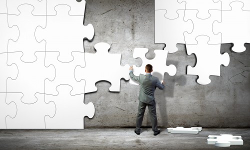 Image of businessman compiling macro white puzzle. Building busi